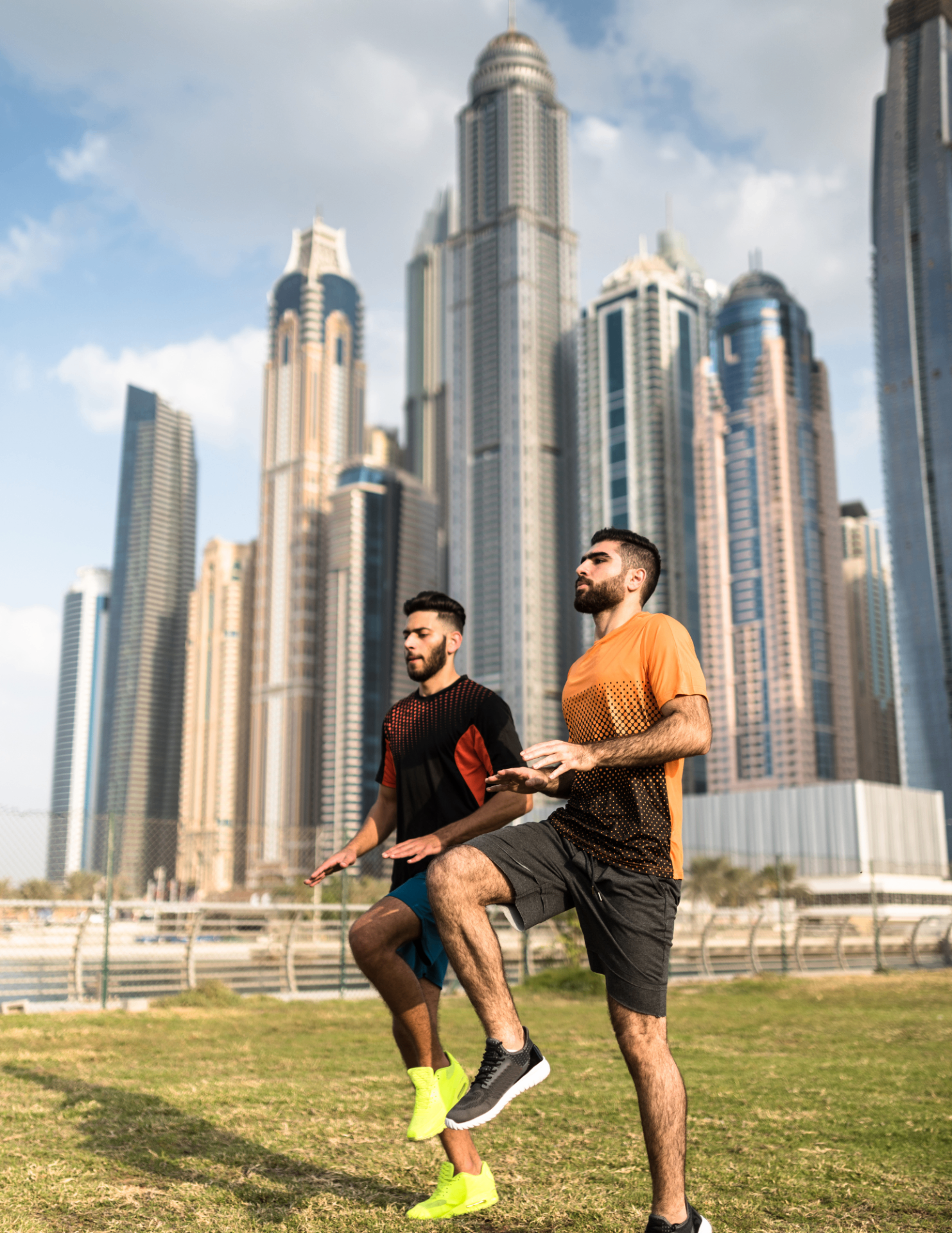 Two men training outdoors in Dubai with the Marina skyline behind